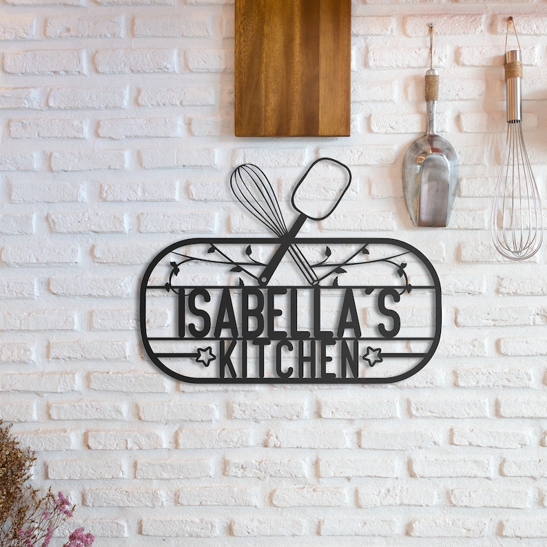 May include: Black metal kitchen sign with the text "Isabella's Kitchen" and a stylized image of a whisk and spatula.