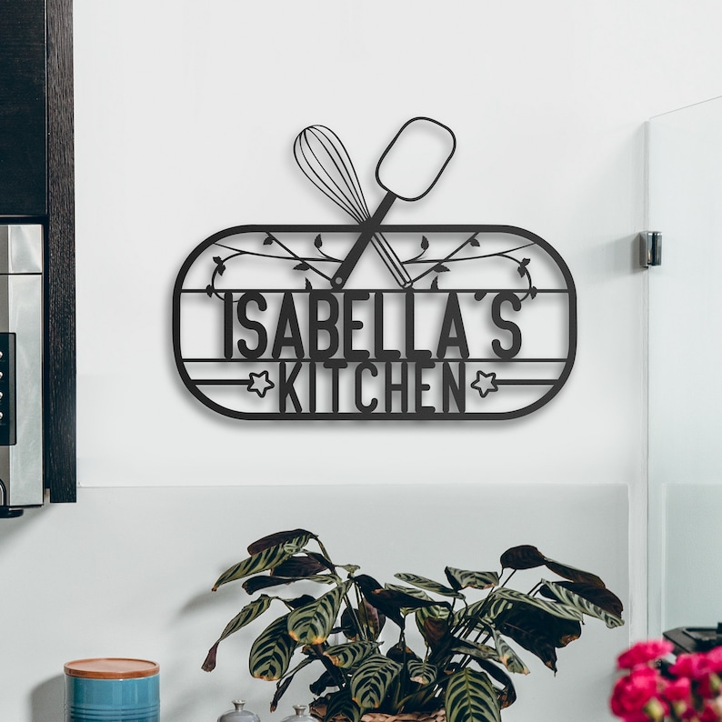 May include: Black metal kitchen sign with the text "Isabella's Kitchen" and a silhouette of crossed kitchen utensils.