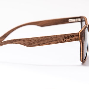 Peut inclure: Lunettes de soleil en bois brun avec une lentille fonc&eacute;e et le nom de la marque "Sixty Six" grav&eacute; sur le c&ocirc;t&eacute;.