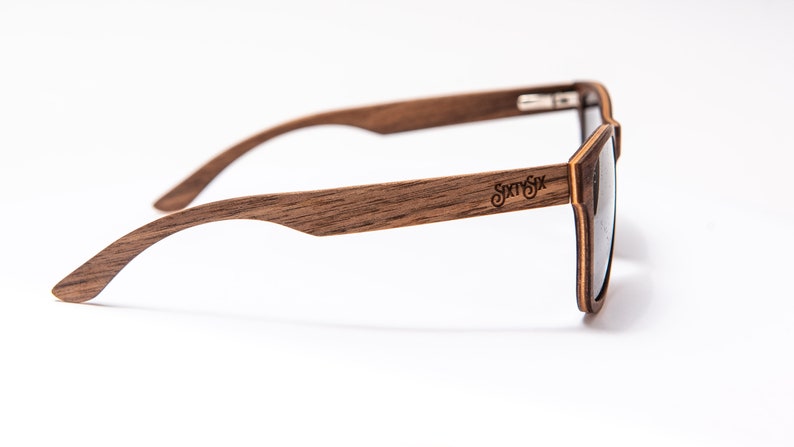 Peut inclure: Lunettes de soleil en bois brun avec une lentille fonc&eacute;e et le nom de la marque "Sixty Six" grav&eacute; sur le c&ocirc;t&eacute;.