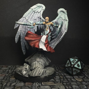 May include: A miniature figurine of a winged warrior with a sword and shield, dressed in red and white robes. The figure stands on a stone base, with a twenty-sided die nearby. The wings are detailed with silver and white.