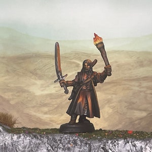 May include: A miniature figurine of a warrior holding a sword and a torch with a flame. The figure is painted in shades of brown and tan, with a detailed design. The background features a desert landscape.