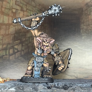May include: A miniature fantasy figure of a creature with a mace and shield. The figure has a furry head, armour, and blue accents. The mace is silver with spikes, and the shield is brown. The figure is standing on a stone base.