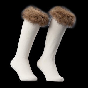 May include: Two off-white knee-high socks with a brown faux fur trim. The socks are set against a black backdrop, accentuating their colour and texture. The fur trim adds a touch of luxury. The socks are approximately 40 cm in length.