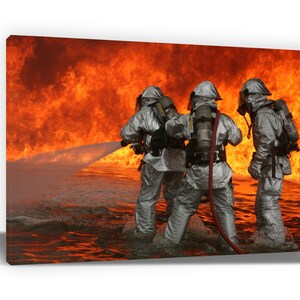 May include: A canvas print depicts three firefighters in protective gear battling a large fire. The firefighters are spraying water from a hose, with flames in the background. The image is a dramatic representation of firefighting.