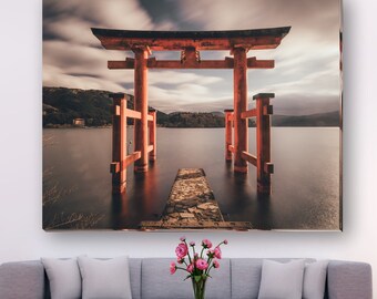 May include: A red wooden torii gate stands in a still body of water. The gate is a traditional Japanese structure often found at the entrance of Shinto shrines.