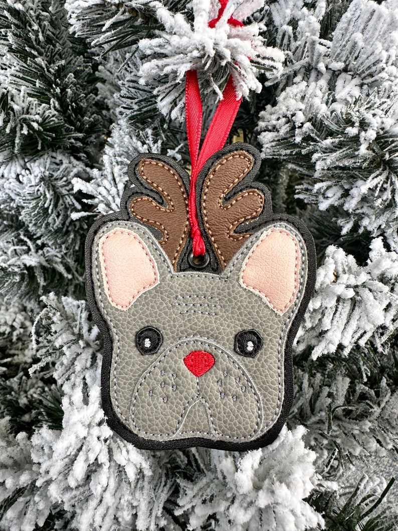 May include: Gray felt Christmas ornament shaped like a French bulldog with brown antlers and a red nose.