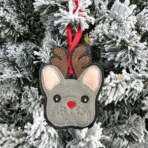 May include: A gray felt Christmas ornament shaped like a French bulldog with brown antlers and a red nose.