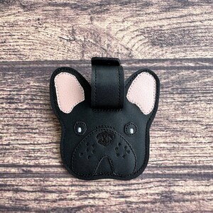 以下が含まれることがあります： フランスのブルドッグの顔のデザインが施された黒い革製の荷物タグ。耳はピンクで、目は白です。
