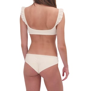 Puede incluir: Bikini blanco con top de volantes y braguita de talle alto.