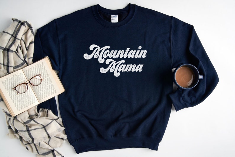 May include: A navy blue sweatshirt with the text "Mountain Mama" in white script lettering.