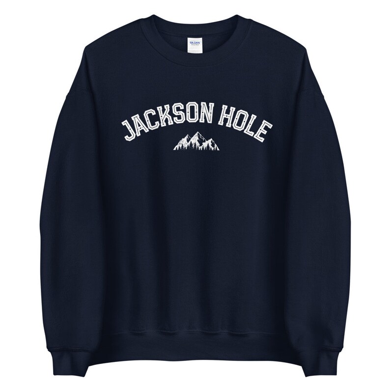 Peut inclure: Un sweat-shirt bleu marine avec le texte "JACKSON HOLE" en blanc et un graphique de montagne blanc.