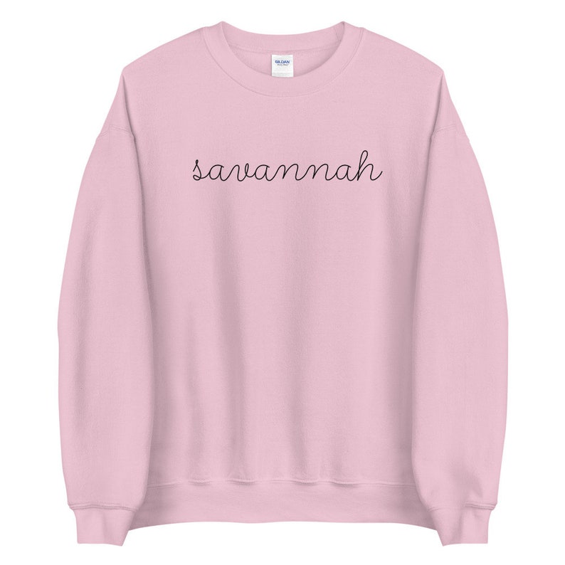 May include: A pink sweatshirt with the word "savannah" written in black cursive script.