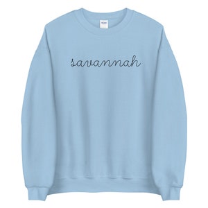 May include: A light blue sweatshirt with the word "savannah" written in black cursive on the front.