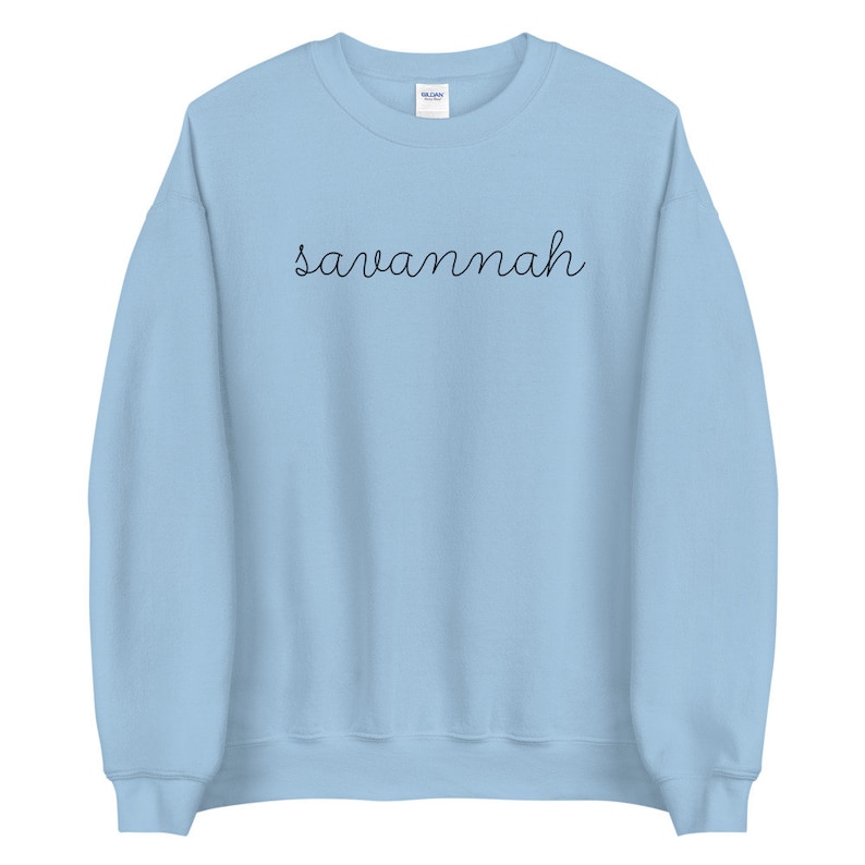 May include: A light blue sweatshirt with the word "savannah" written in black cursive on the front.