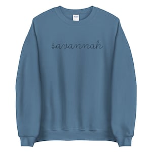 May include: A blue sweatshirt with the word "Savannah" written in black cursive on the front.