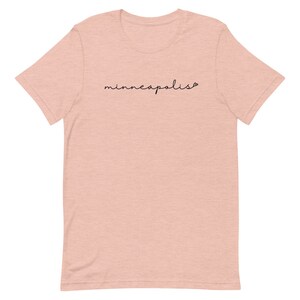 May include: A light pink t-shirt with the word "minneapolis" written in black cursive script.