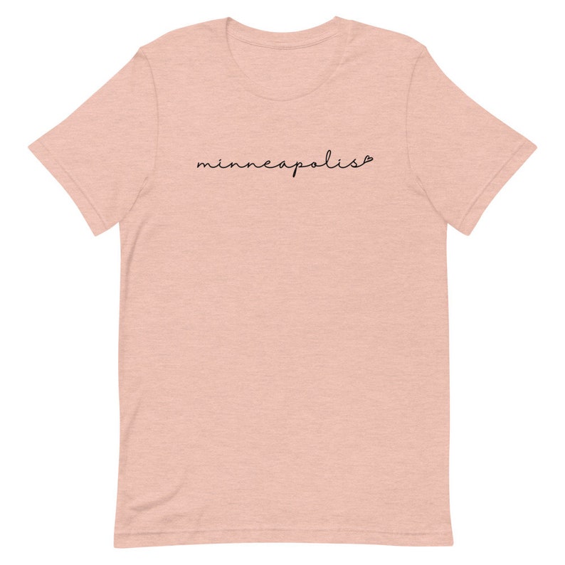 May include: A light pink t-shirt with the word "minneapolis" written in black cursive script.
