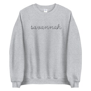 May include: A gray sweatshirt with the word "savannah" written in black cursive on the front.