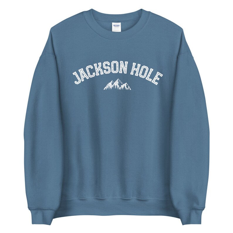 Peut inclure: Un sweat-shirt bleu avec le texte "JACKSON HOLE" en blanc et un graphique de montagne blanc.