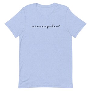 May include: Light blue t-shirt with the text "minneapolis" in black cursive writing.