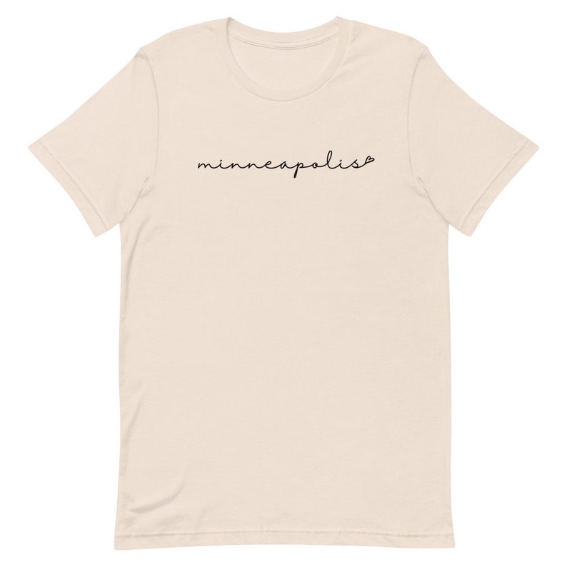 May include: A beige t-shirt with the word "minneapolis" written in black cursive script.
