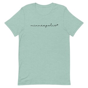 May include: A light blue t-shirt with the word "minneapolis" written in black cursive script.