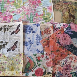 May include: A collection of decorative paper sheets with various floral, botanical, and map designs. The papers feature images of cacti, butterflies, flowers, and a giraffe. Some sheets have text backgrounds, and the color palette includes pink, blue, green, and orange.