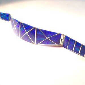 May include: A blue and silver bracelet with a geometric design. The bracelet is made of small pieces of blue opal set in silver.