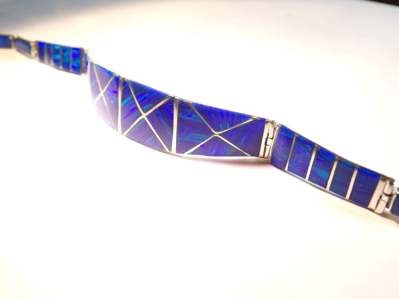 May include: A blue and silver bracelet with a geometric design. The bracelet is made of small pieces of blue opal set in silver.