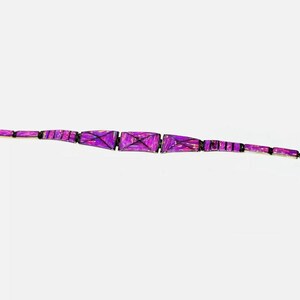 Pode incluir: Uma pulseira roxa com formas geom&eacute;tricas. A pulseira apresenta elos retangulares e trapezoidais em tons de roxo, conectados por elos pretos. O fecho &eacute; prateado. A pulseira tem aproximadamente 18 cm de comprimento.