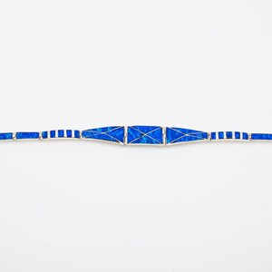 May include: A blue and silver bracelet with a geometric design. The bracelet is made of small, rectangular pieces of blue opal set in silver.