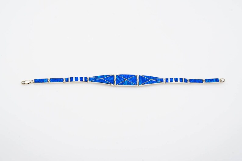 May include: A blue and silver bracelet with a geometric design. The bracelet is made of small, rectangular pieces of blue opal set in silver.