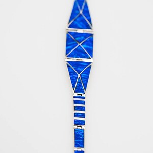May include: A blue and silver bracelet with a geometric design. The bracelet is made of small, rectangular pieces of blue stone set in silver.