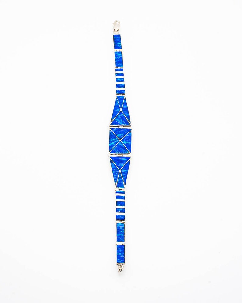May include: A silver bracelet with a geometric design featuring blue opal stones.