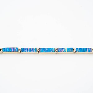 May include: A gold bracelet with blue and pink opal rectangular stones.