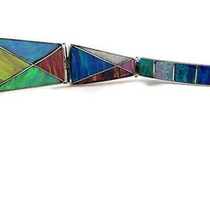 May include: A multi-colored bracelet with geometric shapes made of opal and other gemstones. The bracelet is made of silver and has a clasp.