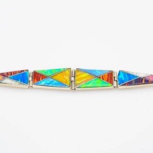 May include: A colorful bracelet made of inlaid opal and silver. The bracelet is made up of five triangular sections, each with a different pattern of opal.