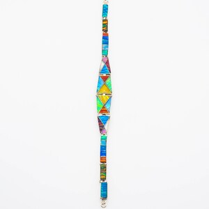 May include: A colorful bracelet with a geometric design made of inlaid opal and silver. The bracelet is made up of a series of triangles and rectangles, each with a different color of opal.