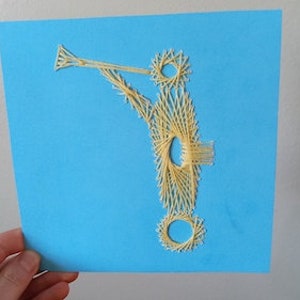 May include: A yellow string art design of a car on a blue background. The car has a rounded body, two wheels, and a long, curved exhaust pipe.