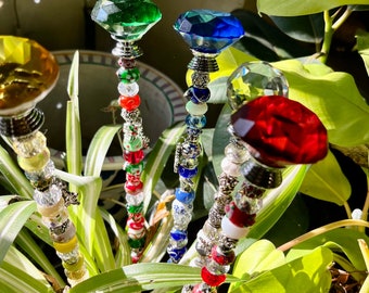 May include: Four decorative garden stakes with colorful glass tops and beaded stems. The tops are green, blue, clear, and red. The beads are silver, white, red, blue, and green.