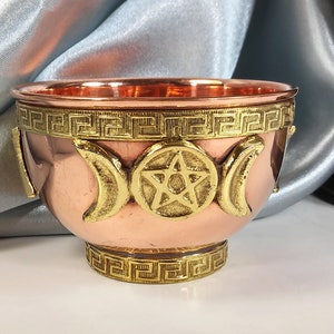 May include: A copper bowl with a gold trim and three crescent moons and a pentagram design.