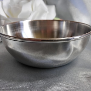 May include: A silver stainless steel bowl with a slightly rounded bottom and a smooth, reflective surface.