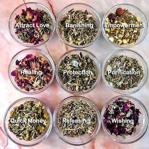 May include: Nine small glass bowls filled with various dried herbs and flowers. Each bowl is labeled with a word such as "Attract Love", "Banishing", "Empowerment", "Healing", "Protection", "Purification", "Quick Money", "Releasing", and "Wishing".
