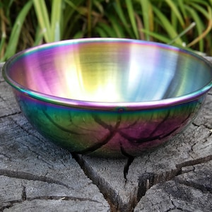 May include: A small, iridescent rainbow-colored metal bowl. The bowl is made of stainless steel and has a smooth, polished finish.