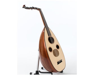 May include: A wooden oud, a Middle Eastern stringed instrument, is displayed on a black and silver stand. The instrument features a light-colored soundboard with three sound holes and a dark, pear-shaped body. The neck curves upward.