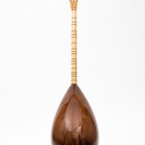 May include: A brown wooden saz, a Turkish stringed instrument, with a pear-shaped body and a long neck with tuning pegs at the top.