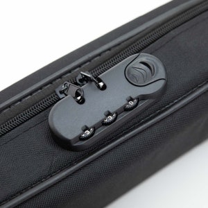 Puede incluir: Una maleta de viaje negra con cremallera y una cerradura de combinaci&oacute;n. La cerradura tiene tres diales con n&uacute;meros del 0 al 9.