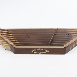 May include: A dark brown wooden santur, a hammered dulcimer, with gold tuning pegs and intricate inlaid designs.