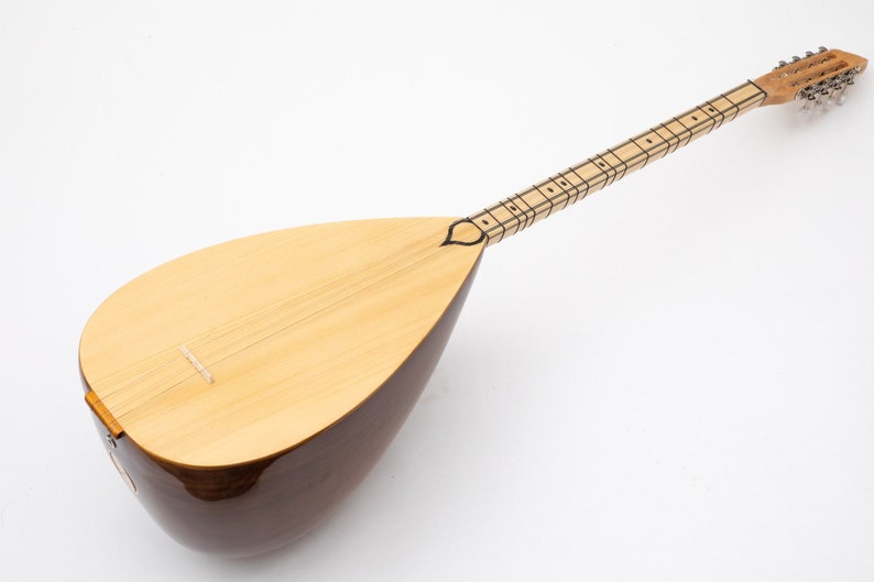 May include: A traditional Turkish stringed instrument called a saz. The saz has a pear-shaped body made of wood and a long neck with frets. The instrument is finished in a natural wood color.